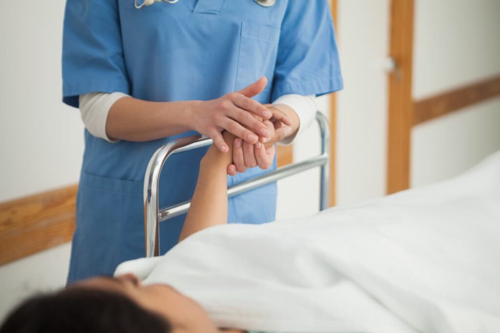 nurse holding the hand of a patient on a gurney